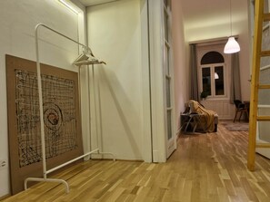 A room with a wooden floor, a white radiator, a white door, and a window with curtains. - MidTerm - Pody Apartment Budapest (Budapest)