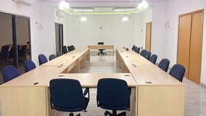 Una sala conferenze con un lungo tavolo, sedie blu e una lavagna.