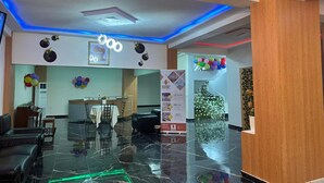 Hall d'albergo con pavimento in marmo, reception, area ristoro con tavolo e sedie, e una scalinata decorata con palloncini colorati.