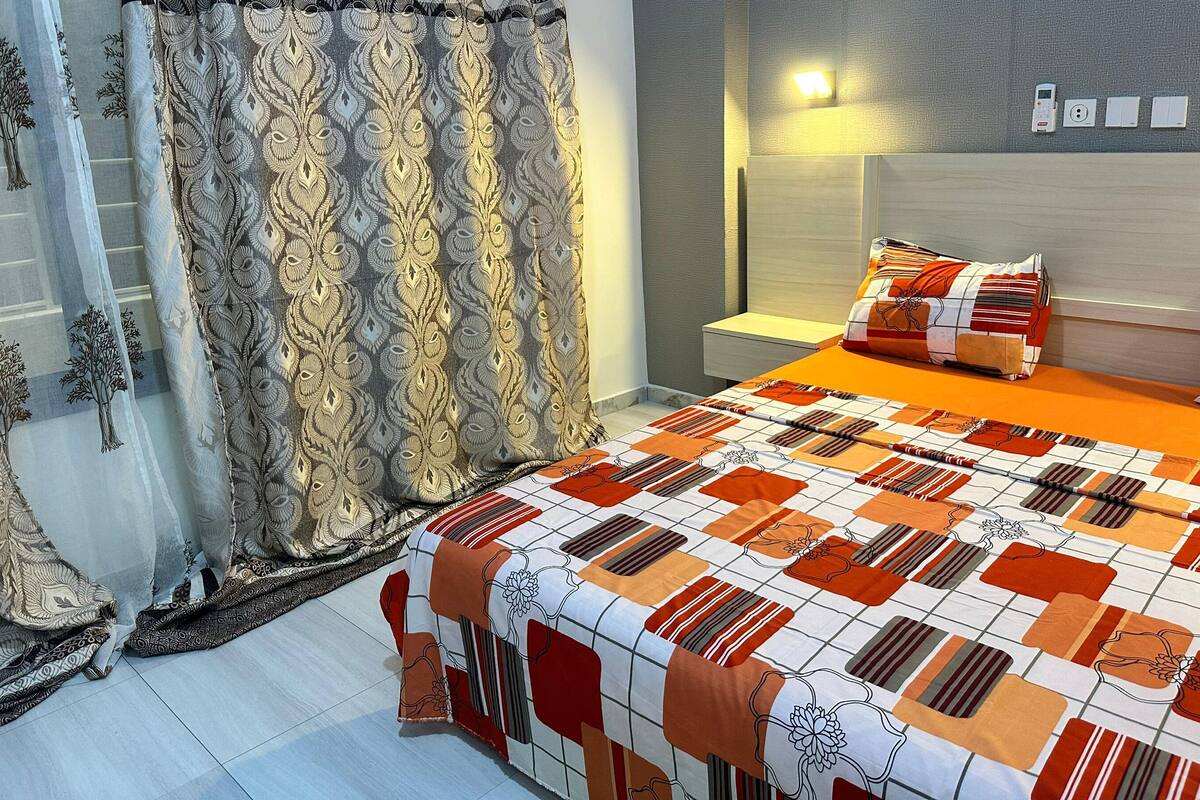 A bedroom with a bed, curtains, a bedside table, and a nightstand.