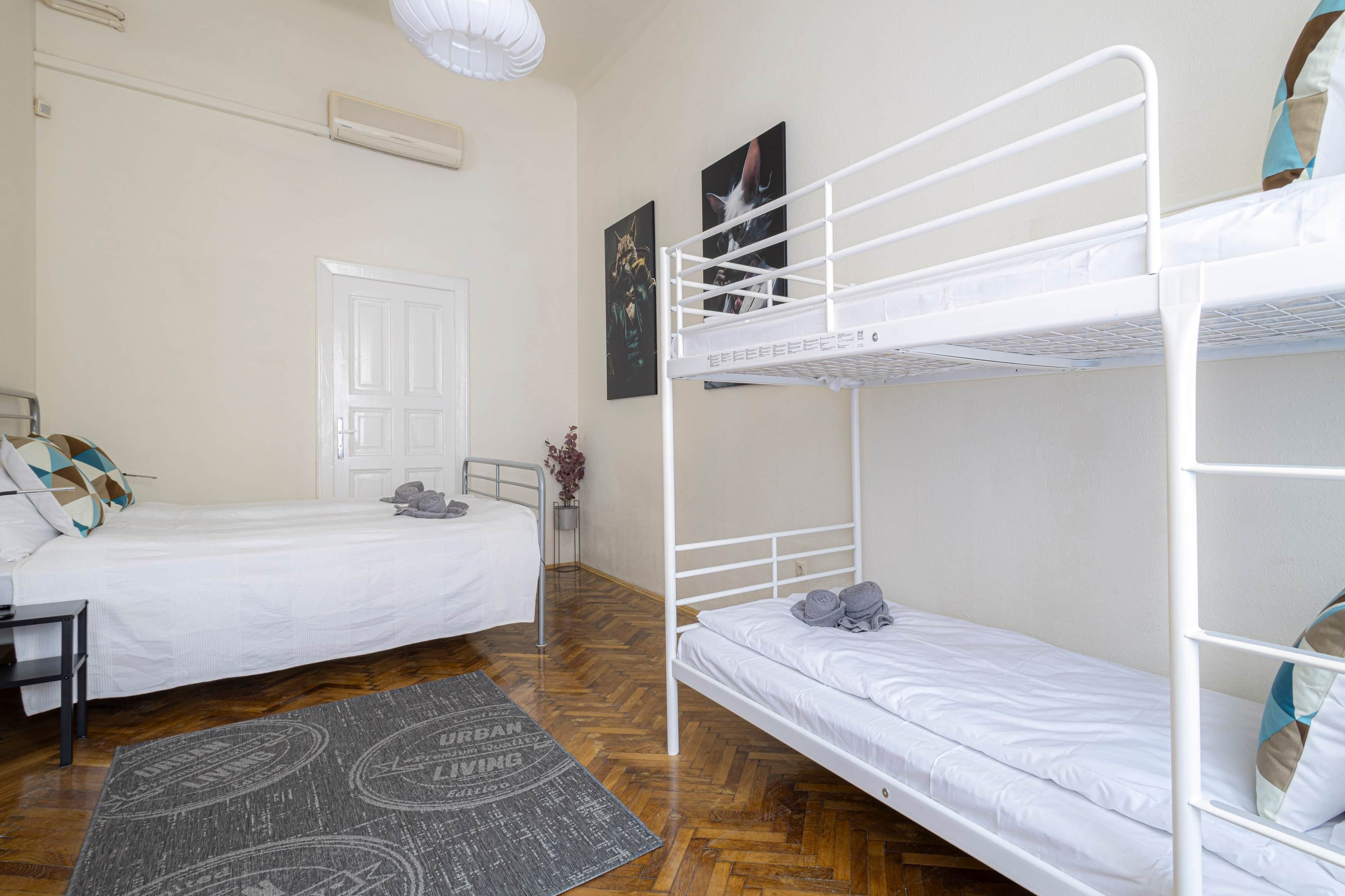 Een kamer met twee stapelbedden, een deur, een radiator en een kleine bloempot.