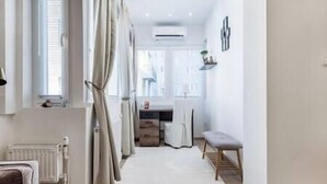 A narrow hallway with a white rug, a radiator, a bench, and a window with curtains. - IMCT - Viktoria design studio apartment with A/C (Budapest)