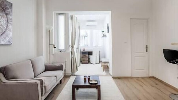 A living room with a sofa, a coffee table, and a TV. There is a door leading to another room. - IMCT - Viktoria design studio apartment with A/C (Budapest)