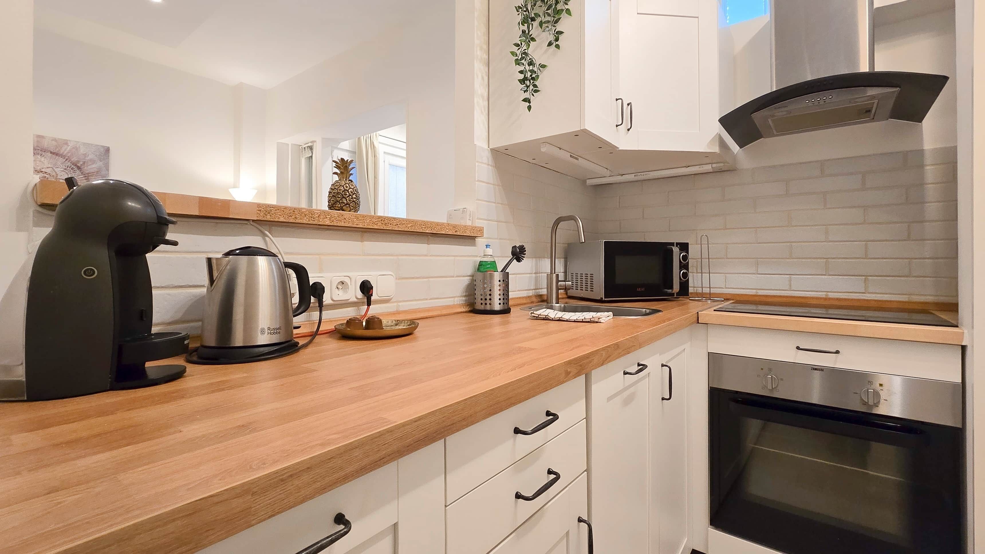 A modern kitchen with a kettle, microwave, and oven.