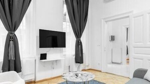 A modern living room with a flat-screen TV mounted on the wall, a round coffee table, and a sofa. - IMCT - Dizsu's Place Budapest (Budapest)