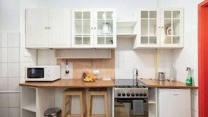 A compact kitchen with white cabinets, a microwave, a stove, and a sink.
