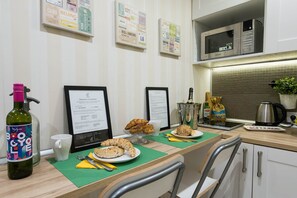 A kitchen area with a microwave, a coffee machine, and a breakfast setup including croissants and a bottle of B&O.