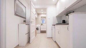 A narrow kitchen with white cabinetry, a washing machine, and a refrigerator. - IMCT - Beautiful Home at Basilica 1 (Budapest)