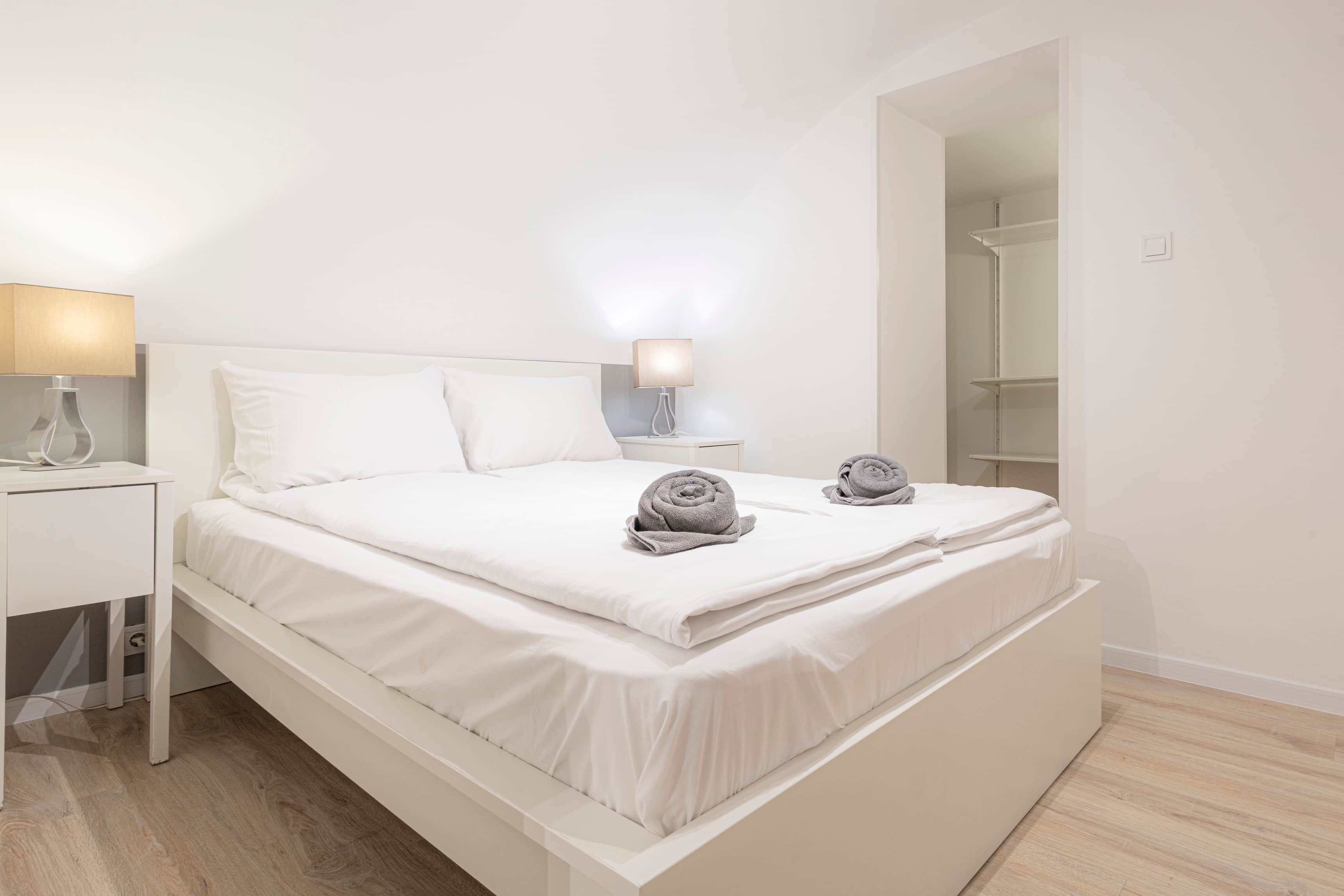 Un dormitorio moderno con cama, mesitas de noche y un armario.