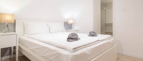 A modern bedroom with a bed, bedside tables, and a wardrobe.