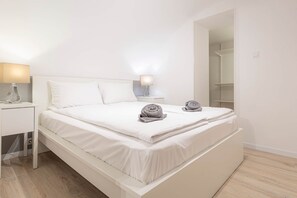 Un dormitorio moderno con cama, mesitas de noche y un armario.