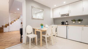 A modern kitchen with white cabinets, a wooden dining table, and a mirror above it.