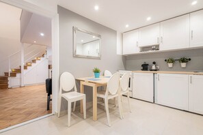 A modern kitchen with white cabinets, a wooden dining table, and a mirror above it.