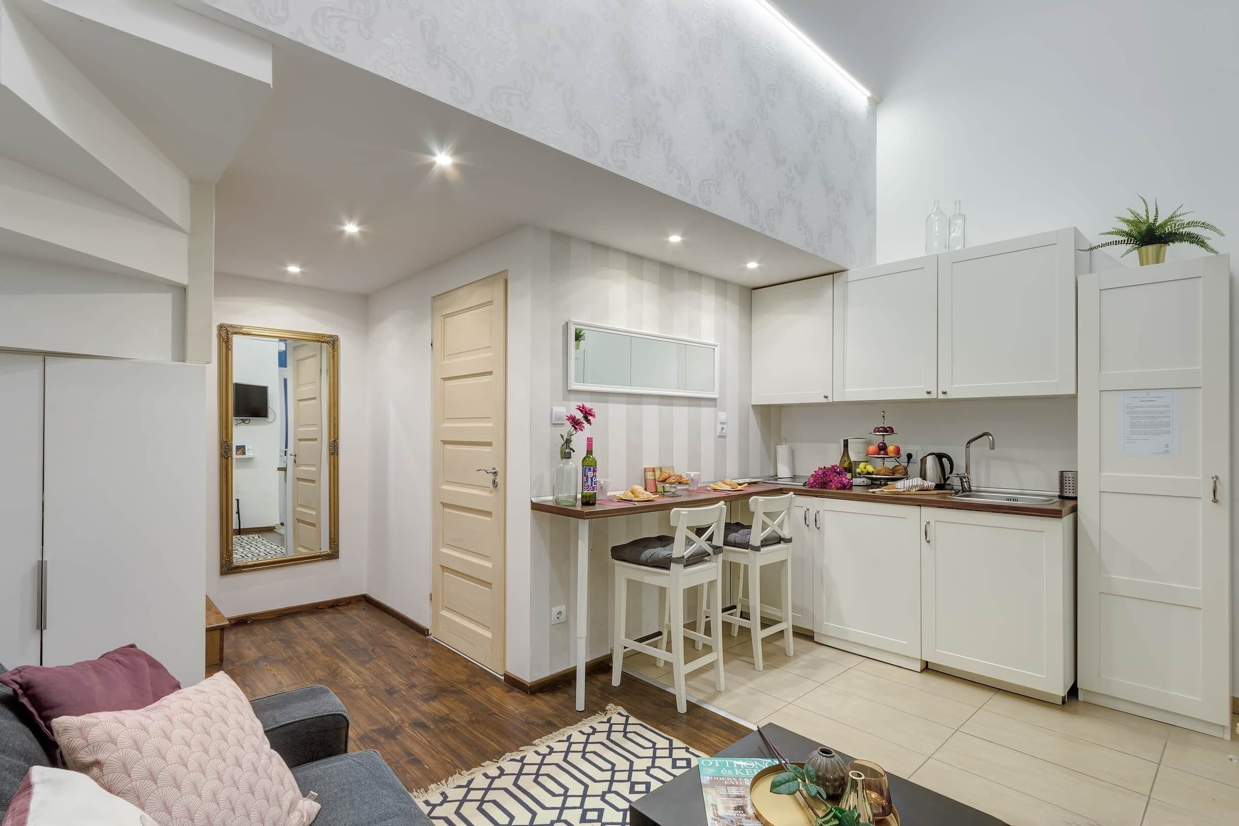 A compact living space with a kitchenette, a dining area, and a seating area with a sofa and ottoman.