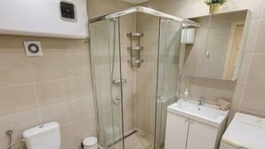 Een moderne badkamer met een douchecabine van glas, een toilet, een wastafel en een spiegel.