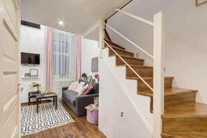A modern living room with a grey sofa, a small coffee table, and a staircase with wooden steps.