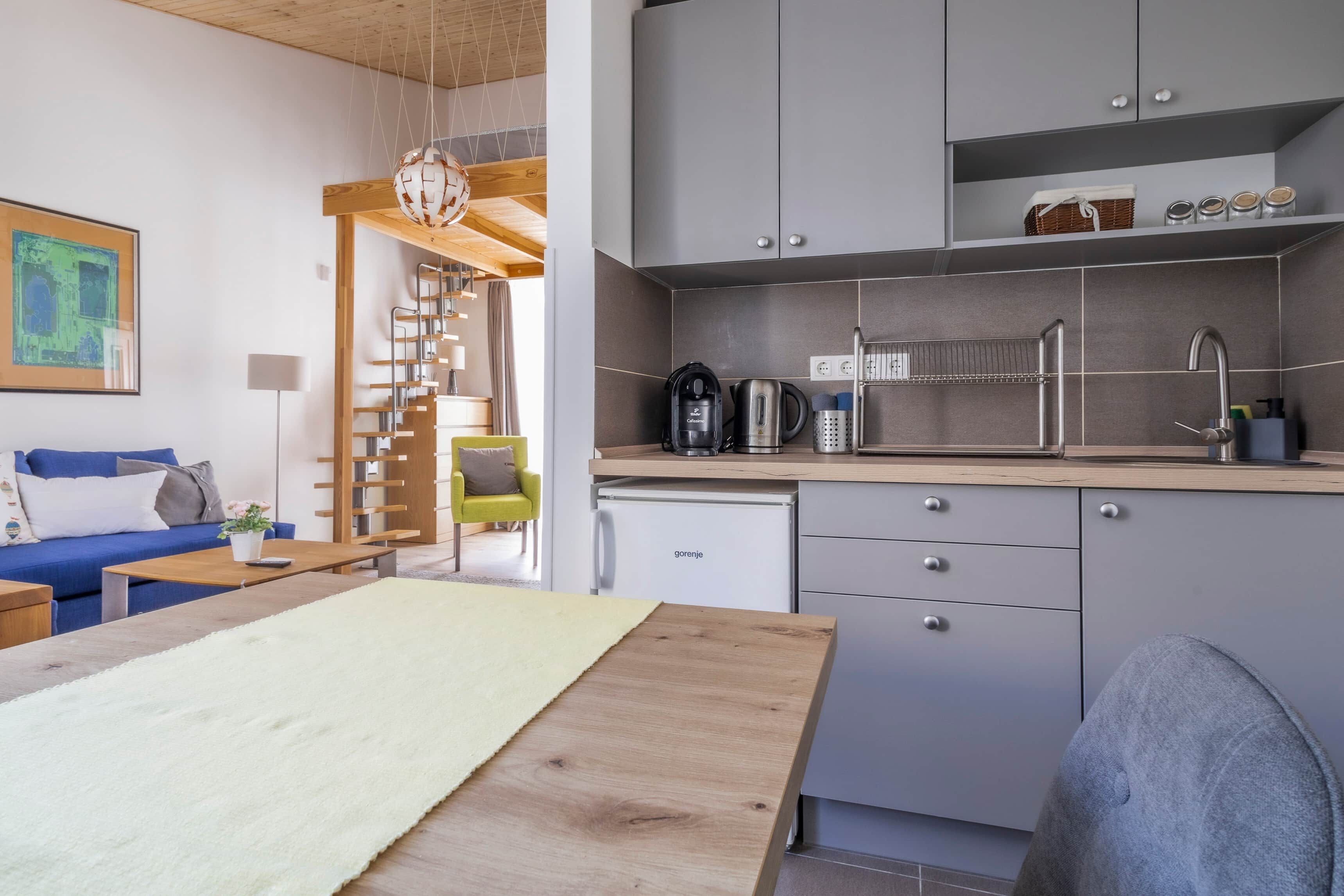 A compact living space with a kitchenette, a dining area, and a staircase leading to an upper level.