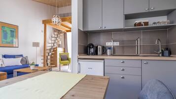 A compact living space with a kitchenette, a dining area, and a staircase leading to an upper level.