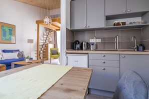 A compact living space with a kitchenette, a dining area, and a staircase leading to an upper level. - Art Gallery Apartman (Siófok)