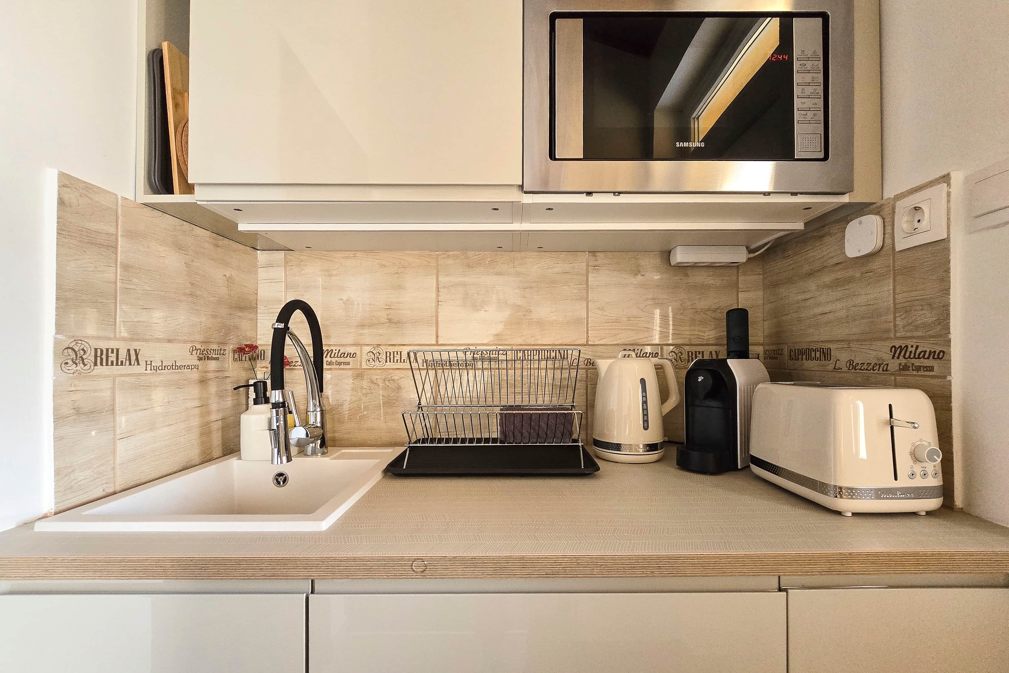 Een moderne keuken met een roestvrijstalen magnetron, een koffiezetapparaat en een broodrooster.