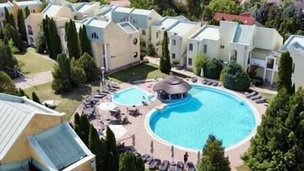 Un complexe résidentiel doté d’une piscine centrale, entourée de chaises longues et agrémenté d’un belvédère.
