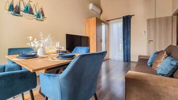 A modern dining area with a wooden table set for four, blue upholstered chairs, and a decorative wall piece.
