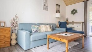 A living room with a blue sofa, wooden coffee table, and a lamp. - LB - MSpirit Apartman Siófok (Siófok)