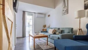 A modern living room with a blue sofa, a wooden coffee table, and a floor lamp. - LB - MSpirit Apartman Siófok (Siófok)