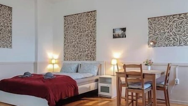 A bedroom with a bed, bedside tables, a desk with a chair, and patterned wall decor. - IMCT - Astoria Apartment Budapest (Budapest)