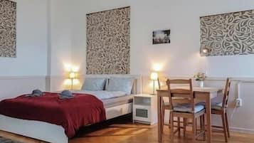 A bedroom with a bed, bedside tables, a desk with a chair, and patterned wall decor.