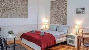 A bedroom with a bed, bedside tables, a chair, a small table with a plant, and decorative wall panels. - IMCT - Astoria Apartment Budapest (Budapest)