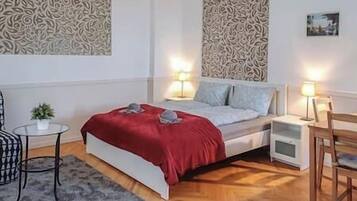 A bedroom with a bed, bedside tables, a chair, a small table with a plant, and decorative wall panels.