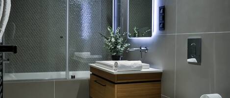 Et moderne badeværelse med toilet, vask og bruseområde.