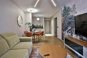 Ein modernes Wohnzimmer mit einer Couch, einem Couchtisch, einem Fernseher und einem Essbereich mit Stühlen und einem Tisch.