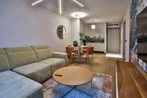 Ein modernes Wohnzimmer mit einer Couch, einem runden Couchtisch und einem Essbereich mit Stühlen.