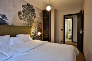 A hotel room with a large bed, a headboard, a wall mural, a door leading to a bathroom, and a floor lamp. - Sun Hill A404 Luxury Suites (Budapest)