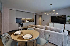 A modern living space with a dining area, kitchen, and entertainment setup. - Sun Hill A201 Luxury Suites (Budapest)