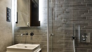 A modern bathroom with a glass-enclosed shower, a wooden vanity, and a large mirror.