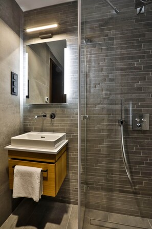 A modern bathroom with a glass-enclosed shower, a wooden vanity, and a large mirror.