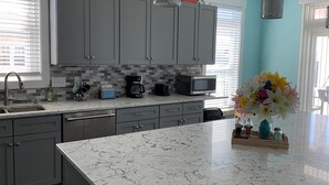 A modern kitchen with grey cabinets, a marble countertop, and a central island.