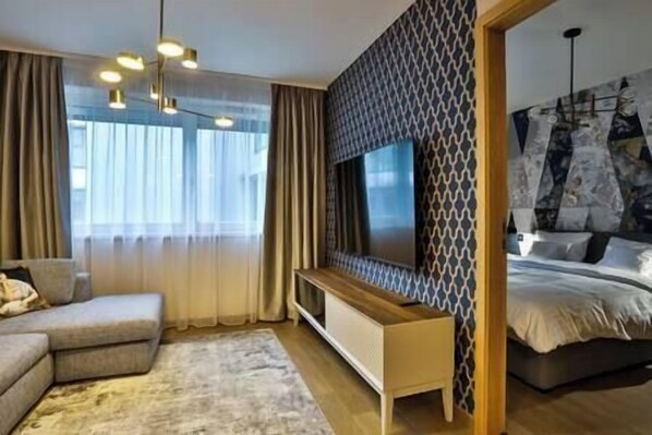 A modern bedroom with a large bed, a TV mounted on the wall, a sofa, and a desk. - IMCT - Sun Hill A307 Luxury Suites (Budapest)