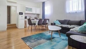 A modern living room with a sofa, a coffee table, and a dining area with chairs and a table. - X - Centrum Charm Apartment (Budapest)