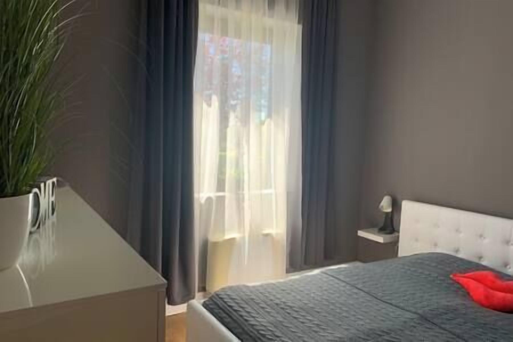 Ein Schlafzimmer mit einem Bett, einem Nachttisch und einem fenster mit Vorhängen.