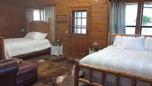 Een kamer in chaletstijl met twee houten bedden, een leren bank en een houten vloer.