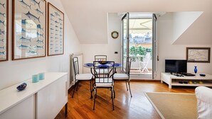 Een moderne woonkamer met een eethoek, met een glazen deur die uitkomt op een balkon met uitzicht op de stad.