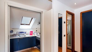 Een kleine keuken met een dakraam, een spoelbak en een kookplaat.