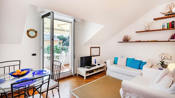 Een moderne woonkamer met een glazen eettafel, een witte bank en een tv-meubel.
