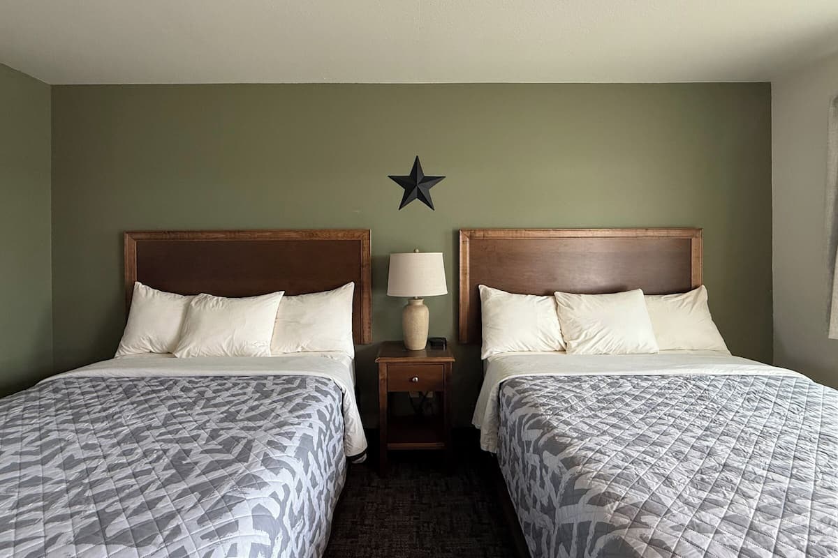 A hotel room with two beds, a star decoration on the wall, and a nightstand with a lamp.