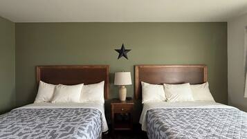 Una habitación de hotel con dos camas, una decoración con forma de estrella en la pared y una mesita de noche con lámpara.