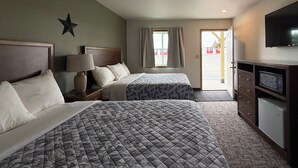 Een hotelkamer met twee bedden, een televisie, een bureau en een raam met gordijnen.